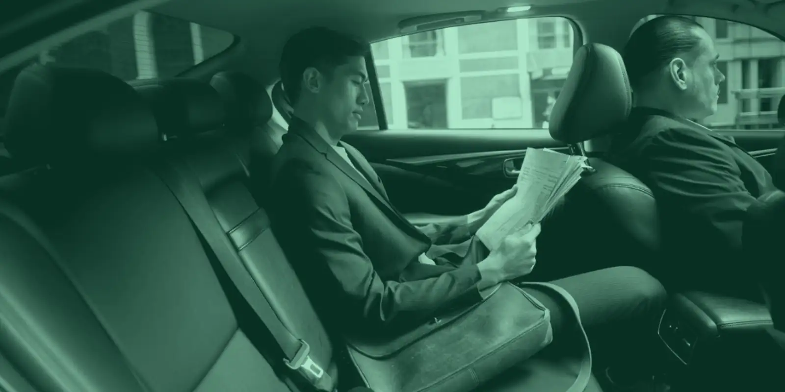 Business passenger reading in the back of a chauffeur-driven car